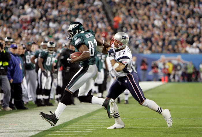 Philadelphia Eagles receiver Terrell Owens runs with the ball as New England Patriots defensive back Rodney Harrison approaches to try to tackle him